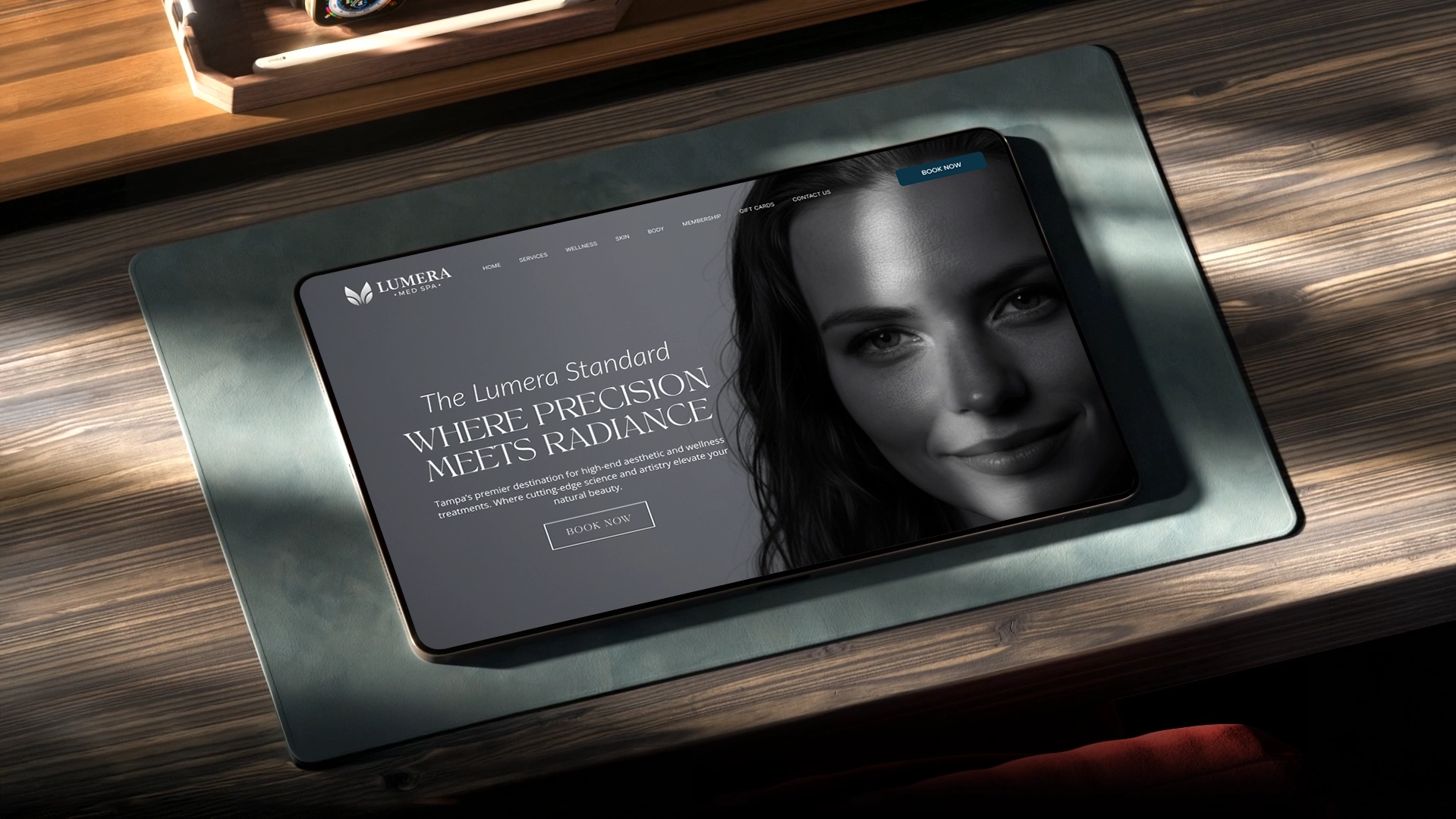 Tablet displaying Lumera Med Spa homepage on a dark textured surface